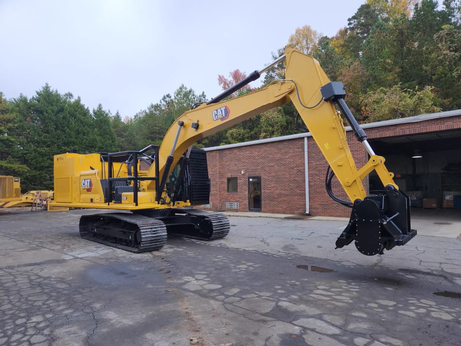 CAT 330 excavator with Powertek-built power pack and mulching head, boom raised outside the Concord shop