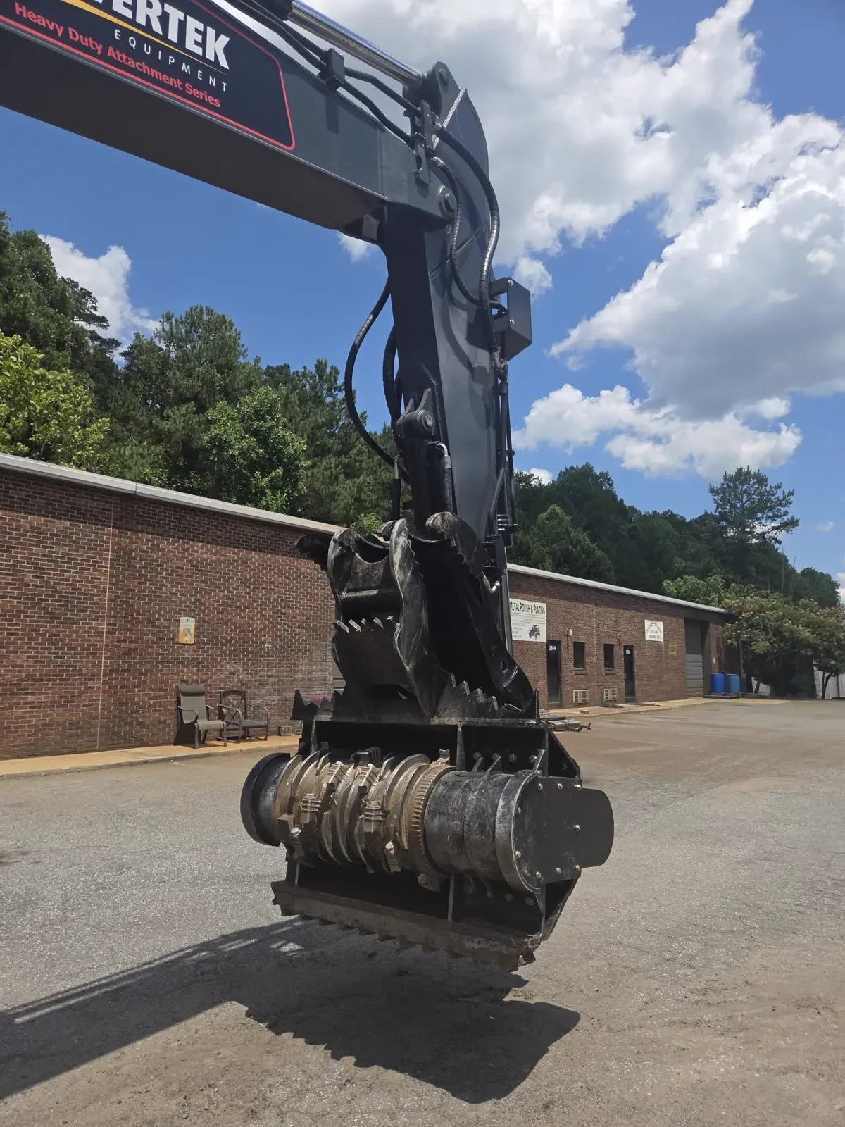Powertek cutterhead drum and hydraulic thumb on an excavator arm, front view