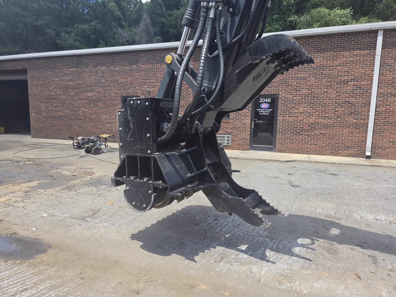 Powertek cutterhead with hydraulic thumb and drive mounted on an excavator arm, side view